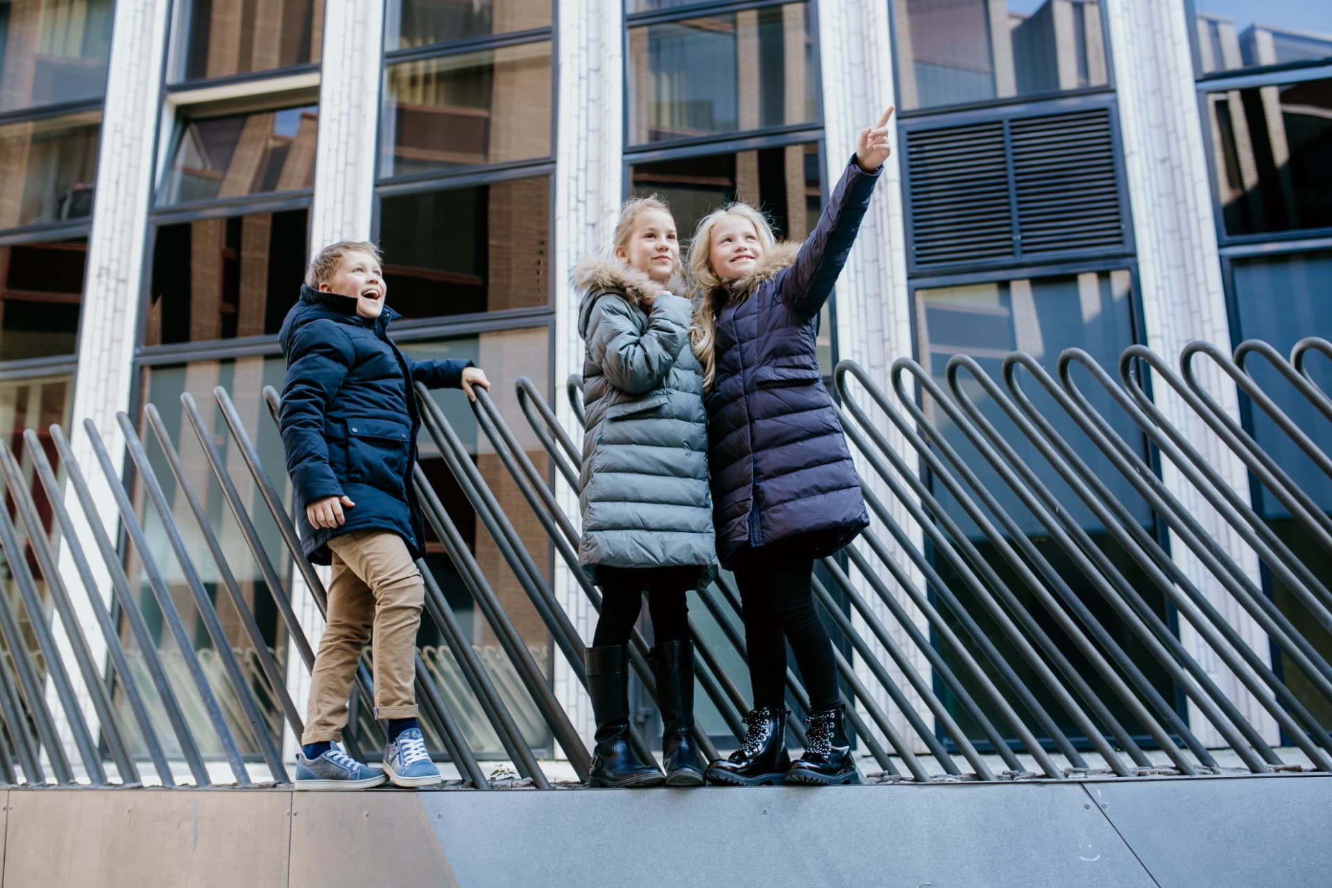 Three children in Pengu KIDS down jackets in the city on a winter day